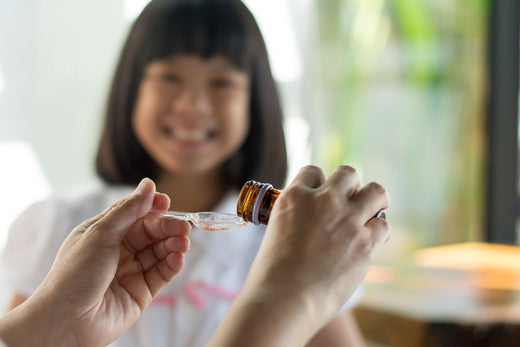 Mother giving her little smiling girl a teaspoon of fish oil for Autism.