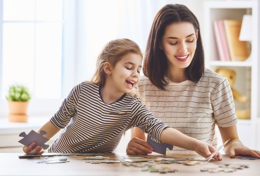 Mother and daughter do puzzles together on their kitchen table.